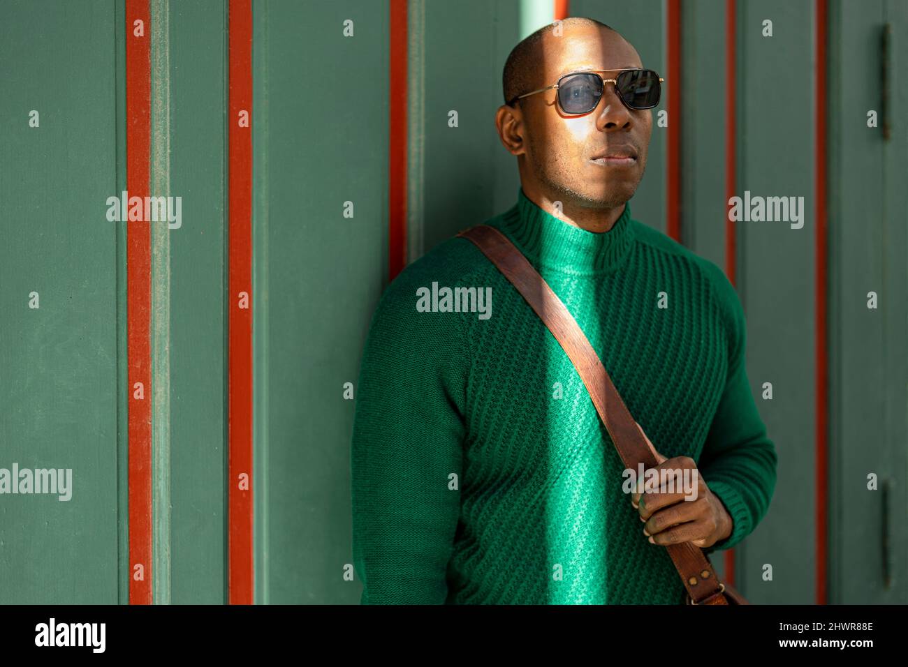 Mann mit Sonnenbrille, der vor der Wand steht Stockfoto