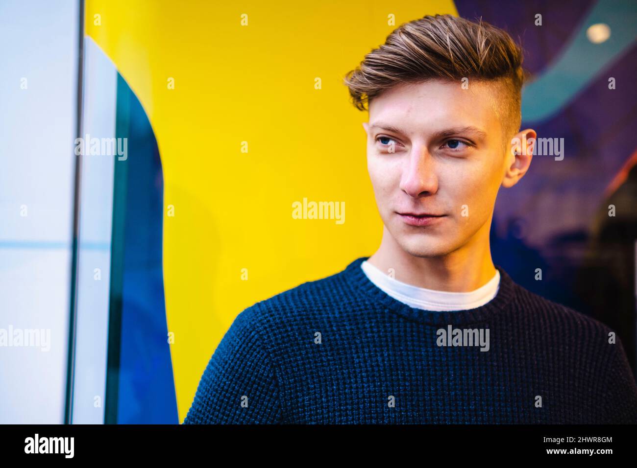 Hübscher Mann, der vor der Wand steht Stockfoto