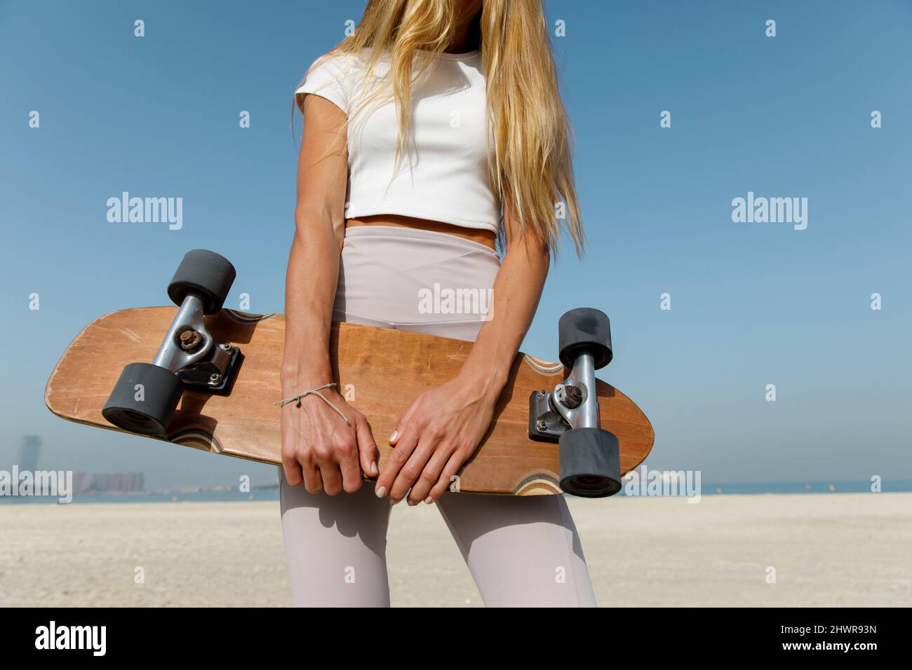 Frau mit einem hölzernen Skateboard am Strand Stockfoto