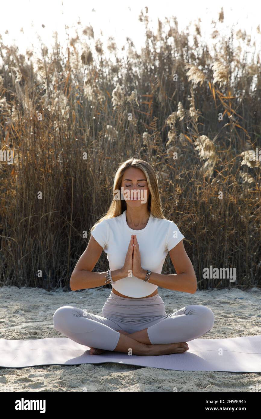 Frau in Meditation Pose auf Yogamatte am Strand Stockfoto
