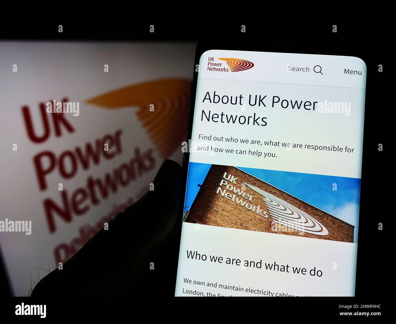 Person mit Mobiltelefon und Webseite des britischen Elektrizitätsunternehmens UK Power Networks auf dem Bildschirm mit Logo. Konzentrieren Sie sich auf die Mitte des Telefondisplays. Stockfoto