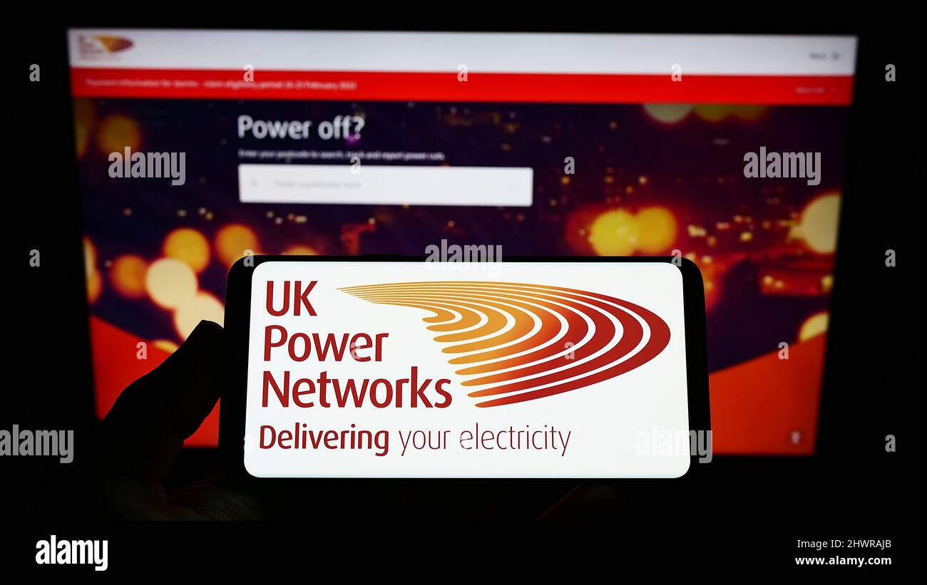 Person, die das Smartphone mit dem Logo des britischen Elektrizitätsunternehmens UK Power Networks auf dem Bildschirm vor der Website hält. Konzentrieren Sie sich auf die Telefonanzeige. Stockfoto