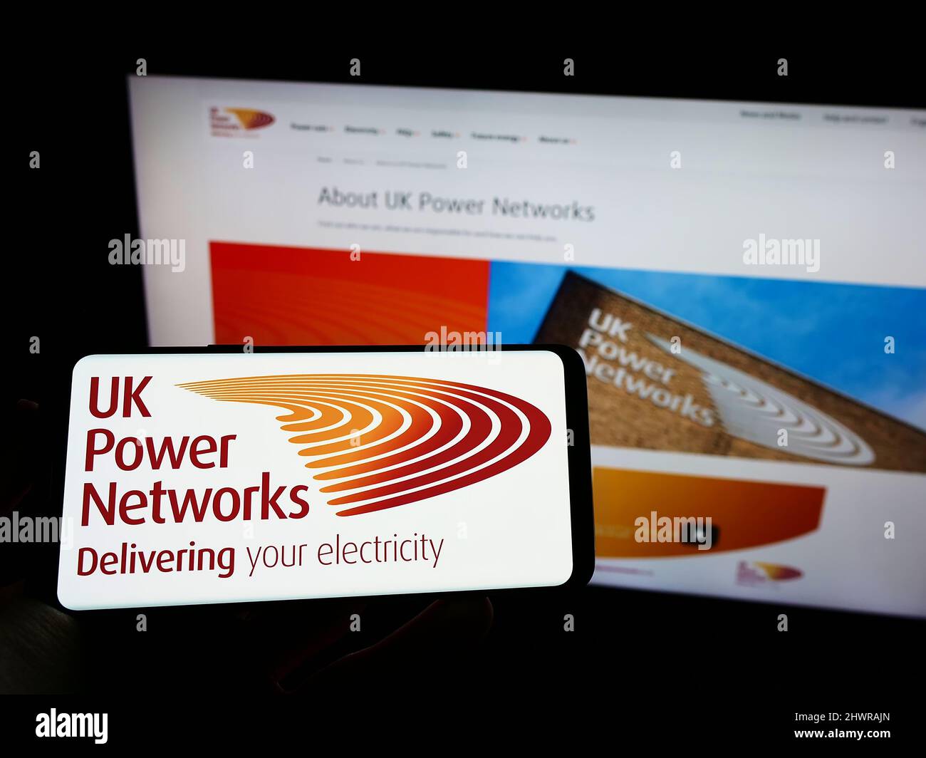 Person mit Mobiltelefon und Logo des britischen Elektrizitätsunternehmens UK Power Networks auf dem Bildschirm vor der Webseite. Konzentrieren Sie sich auf die Telefonanzeige. Stockfoto