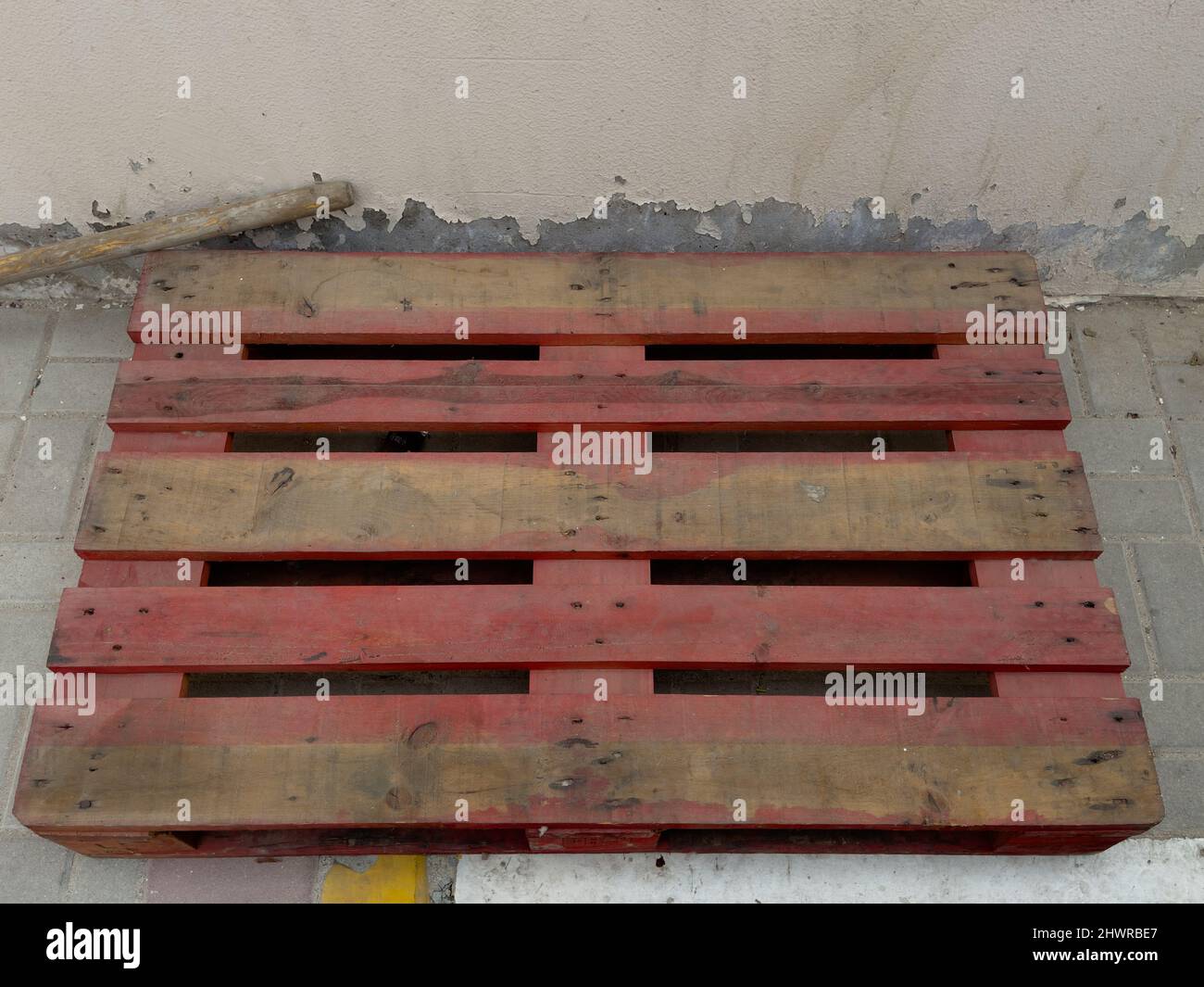 Eine einzelne Holzpalette links zufällig auf der Seite eines Fußweges. Abfallrecycling- und -Managementkonzept. Stockfoto