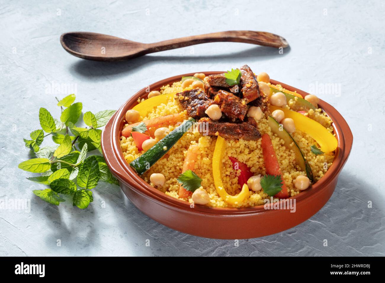 Fleisch- und Gemüsesorten Couscous, traditionelle marokkanische Küche, mit frischem Koriander und Minze. Festliches arabisches Gericht Stockfoto
