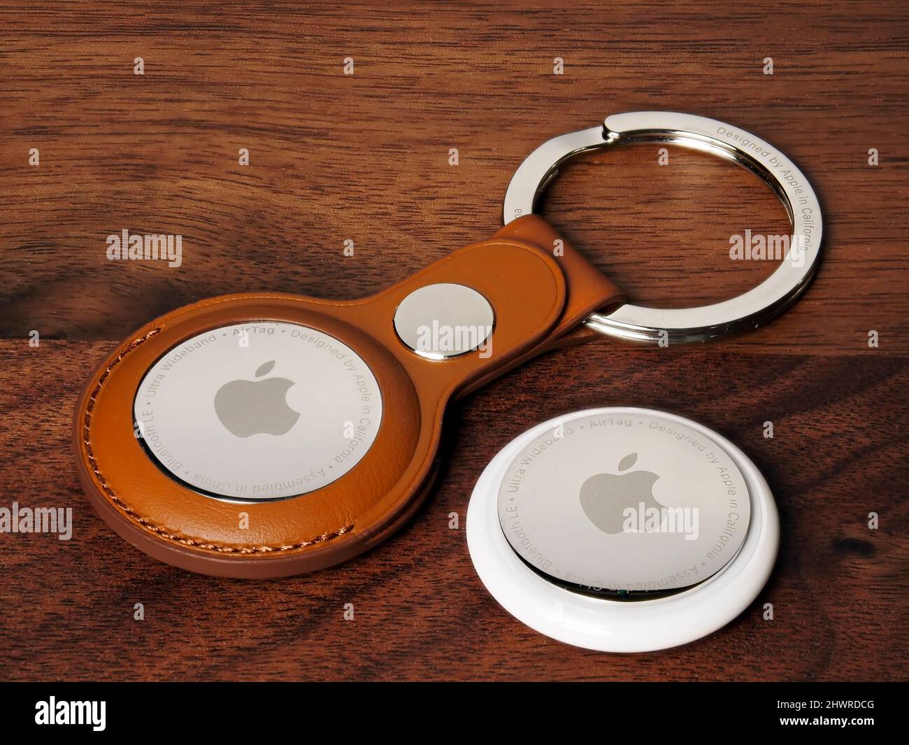 Bukarest, Rumänien - 6. März 2022: Apple Air Tags mit braunem Lederschlüsselbund, auf Holzhintergrund Stockfoto