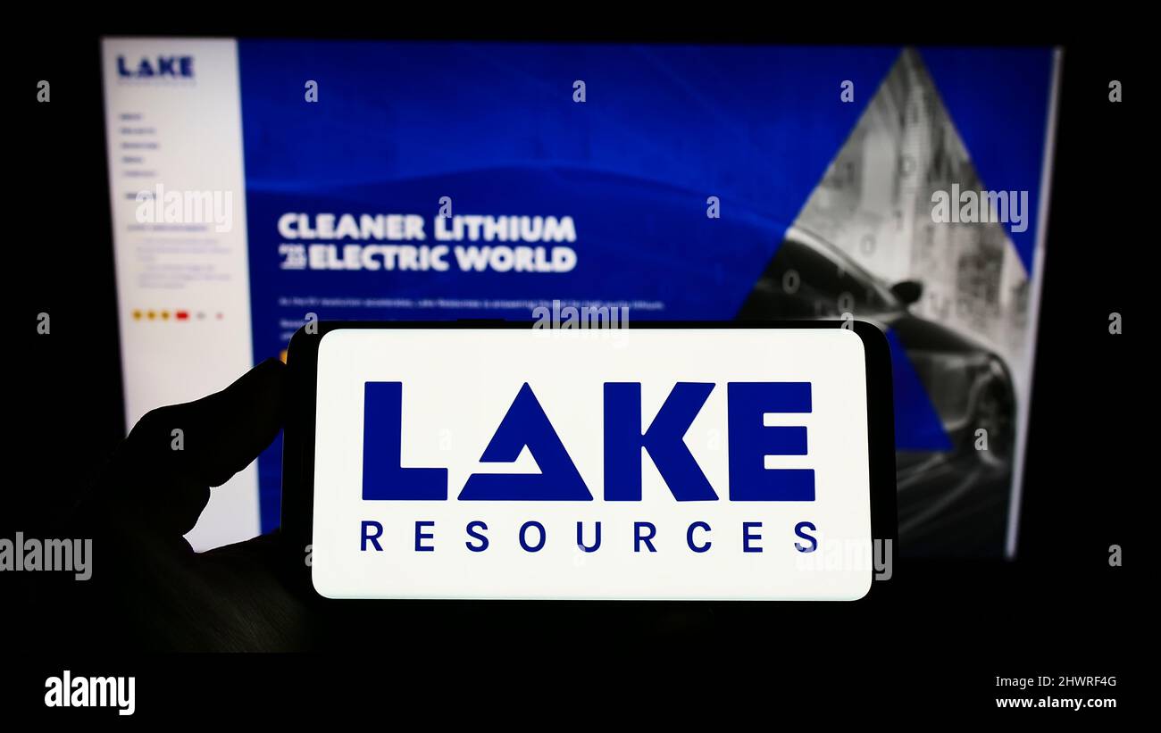 Person mit Mobiltelefon und Logo des australischen Lithiumunternehmens Lake Resources NL auf dem Bildschirm vor der Business-Webseite. Konzentrieren Sie sich auf die Telefonanzeige. Stockfoto