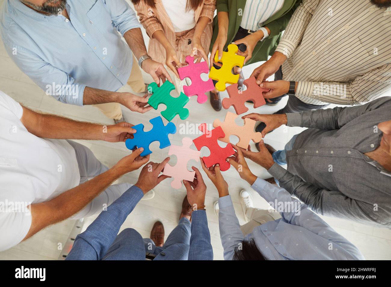 Team von Geschäftsleuten, die Puzzleteile verbinden, um das Konzept der Teamarbeit zu veranschaulichen Stockfoto