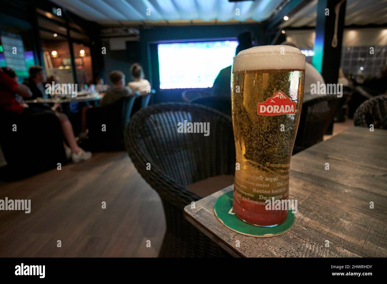 Bier von dorada mit Touristen, die in einer Bar in playa blanca, lanzarote, kanarische Inseln, spanien, ein Fußballspiel der Champions League beobachten Stockfoto