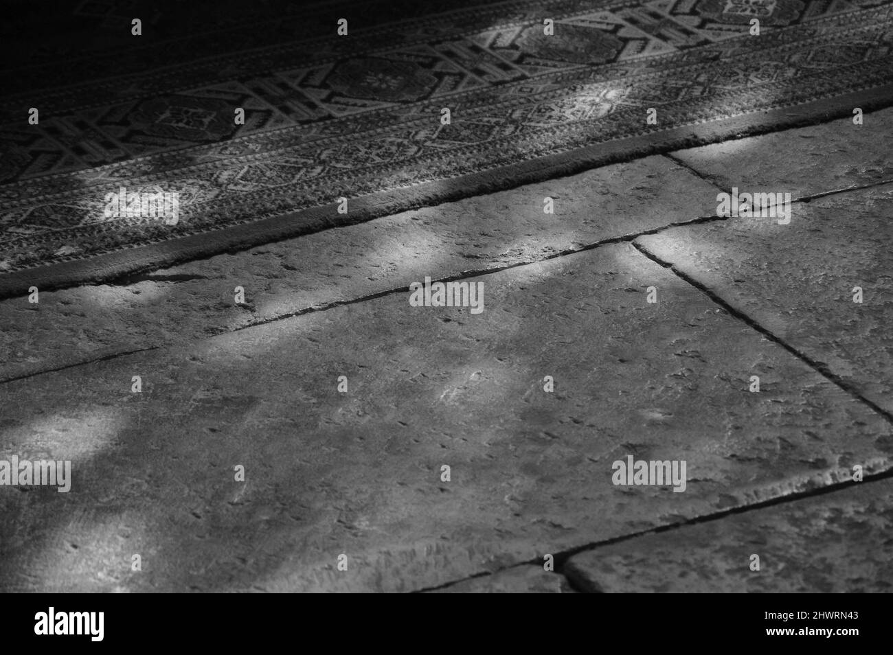 Lichtflecken auf dem Boden und Teppich in der Kirche. Sonnenlicht filterte durch das Buntglasfenster. Ein Spiel von Licht und Schatten. Gealtertes Foto. Schwarz A Stockfoto