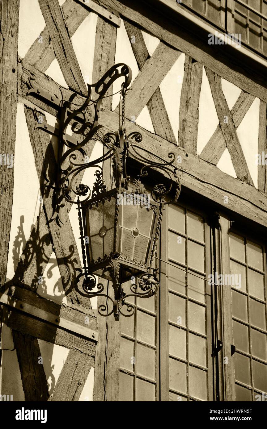 Antike Laterne, die auf einem Fachwerkhaus in der mittelalterlichen Stadt Auxerre, Burgund, Frankreich, hängt. Sepia historisches Foto. Stockfoto