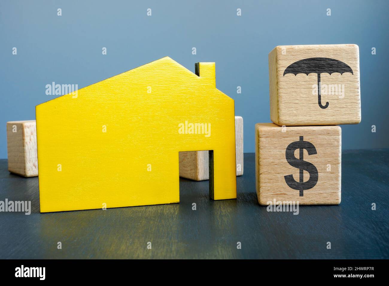 Konzept der Sachversicherung. Haus und Würfel mit Regenschirm. Stockfoto