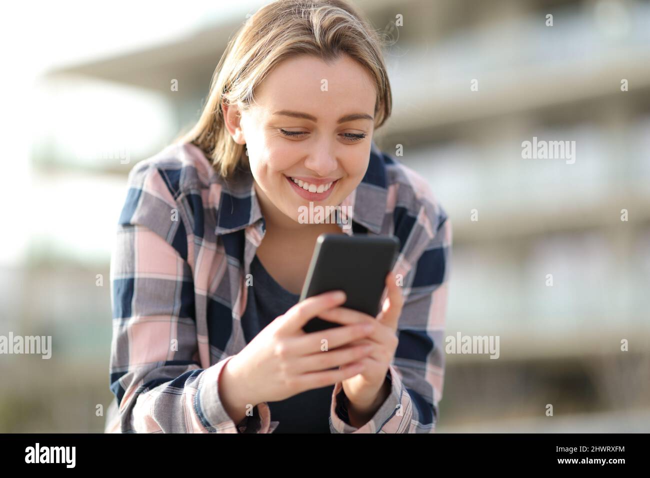 Fröhlicher Teenager, der auf der Straße Smartphone-Inhalte überprüft Stockfoto