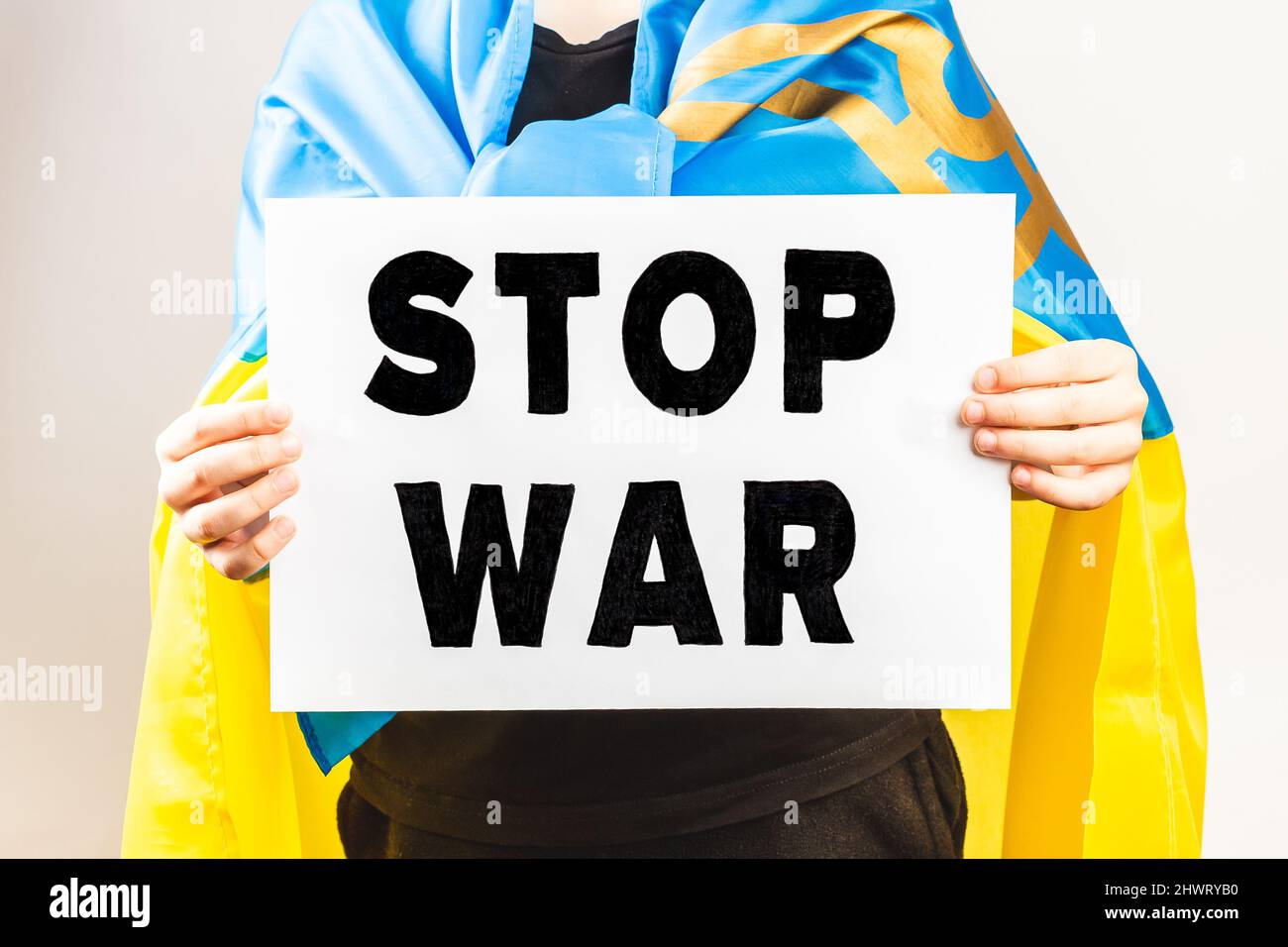 Der mit ukrainischer Flagge gewickelte Protestler hält ein Demonstrationsschild mit der Botschaft „Stop war“. Protest gegen Russland Angriff auf die Ukraine Stockfoto