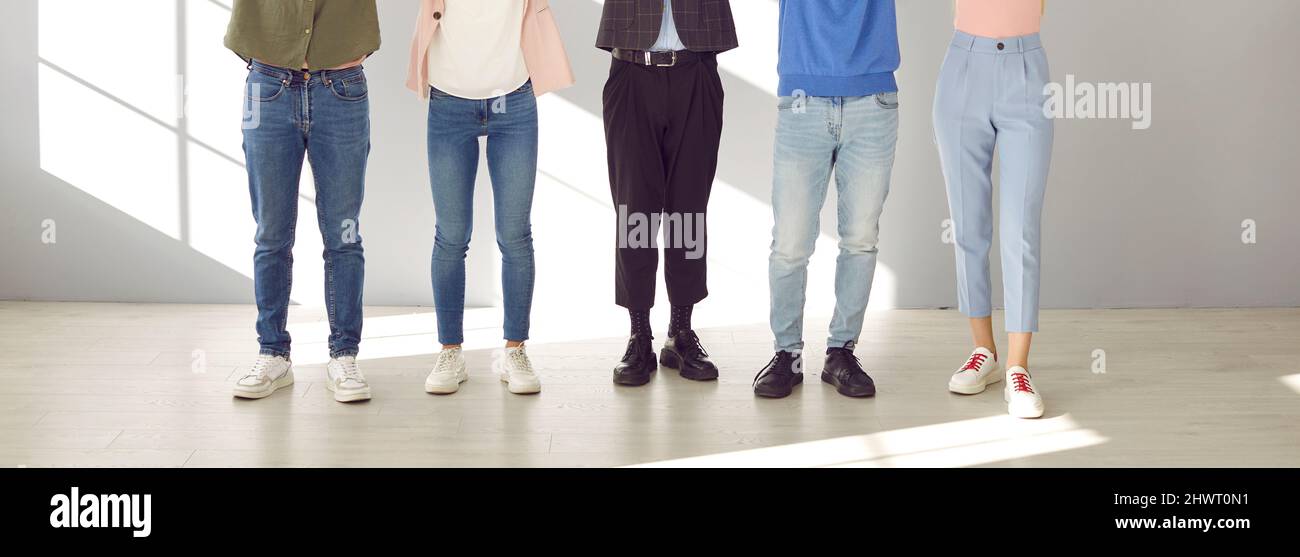 Team von jungen Männern und Frauen, die Jeans und Hosen tragen, stehen zusammen im Büro Stockfoto