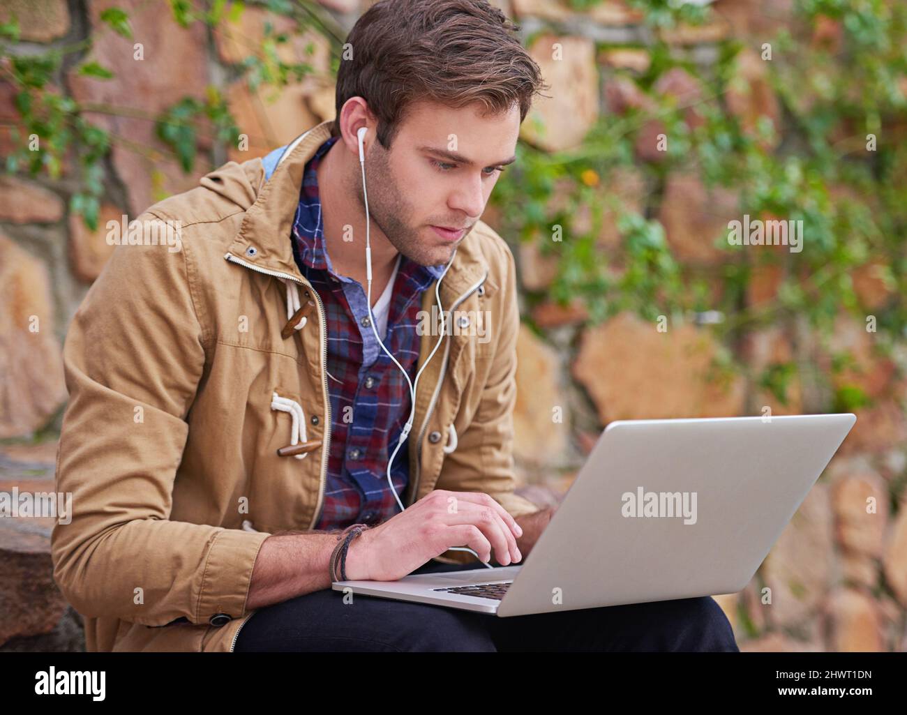 HES ein engagierter Student. Aufnahme eines hübschen männlichen Studenten, der seinen Laptop auf dem Campus benutzt. Stockfoto