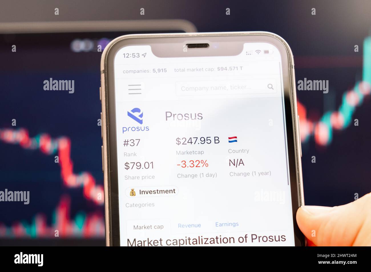 Prosus Aktienkurs auf dem Bildschirm des Mobiltelefons in mans Hand mit wechselnden Börsengraphen im Hintergrund, Februar 2022, San Francisco, USA. Stockfoto