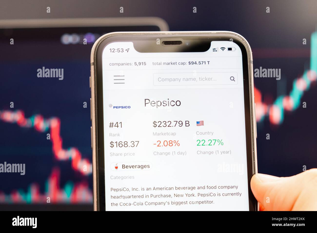 PepsiCo-Aktienkurs auf dem Bildschirm des Mobiltelefons in mans Hand mit wechselnden Börsengraphen im Hintergrund, Februar 2022, San Francisco, USA. Stockfoto