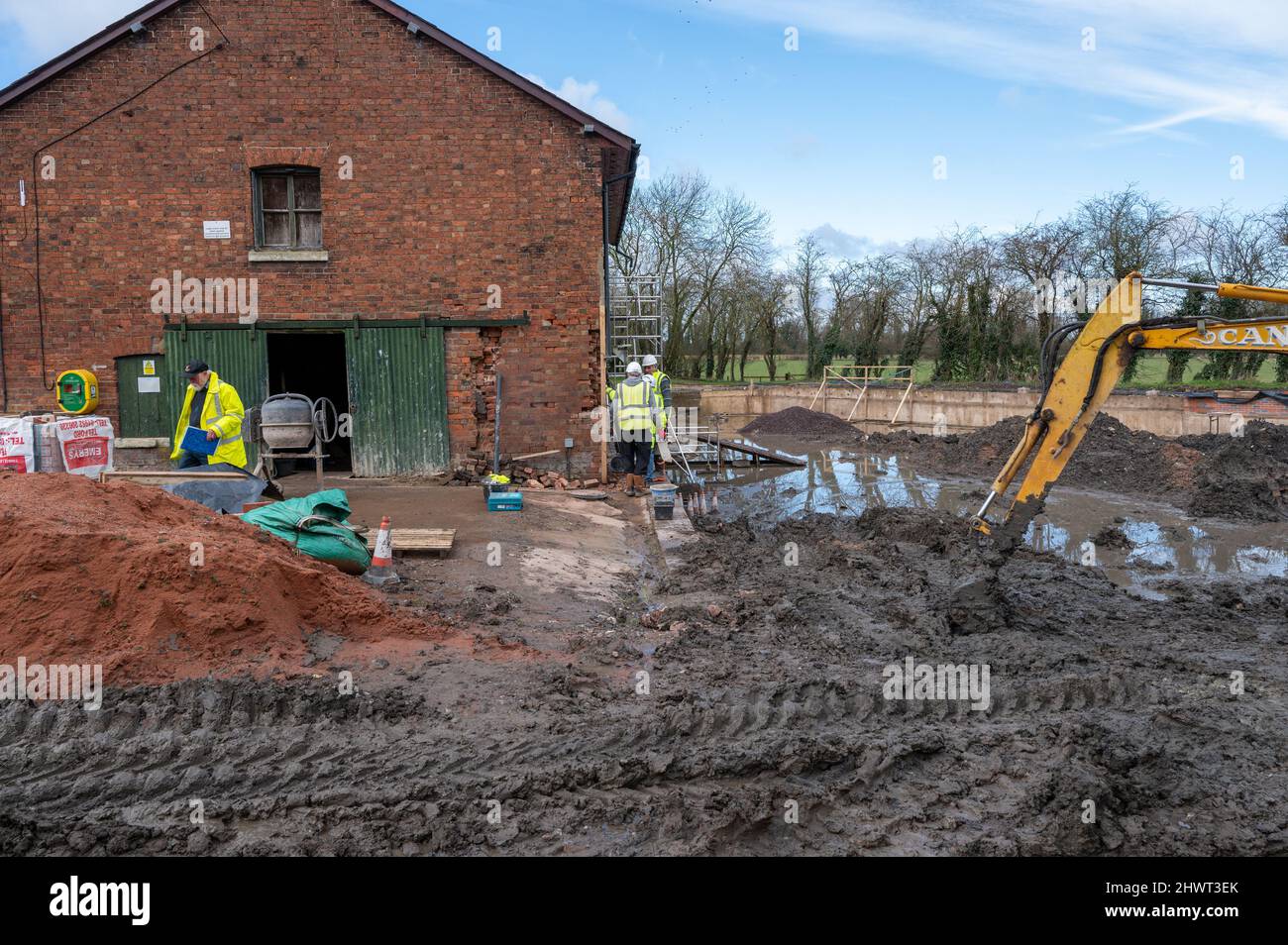 An einem Kanalbecken und angrenzenden Lagerhäusern werden von Freiwilligen in Wappenshall, Telford, Shropshire, Großbritannien, Restaurierungsarbeiten durchgeführt Stockfoto