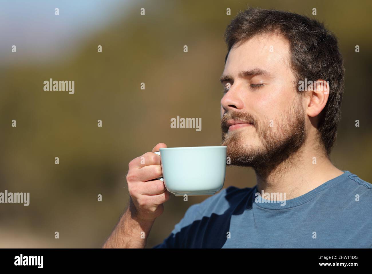 Entspannter Mann, der in der Natur eine Tasse Kaffee genießt Stockfoto