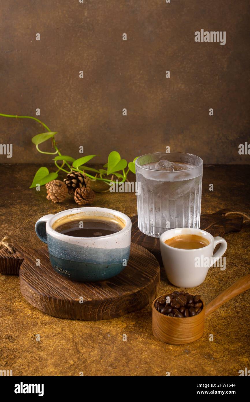 Ein aromatischer Kaffee, der frisch zum Ausgießen gemahlen wird, wird auf einem rustikalen Holztablett zu heißem oder kaltem schwarzen Kaffee Stockfoto
