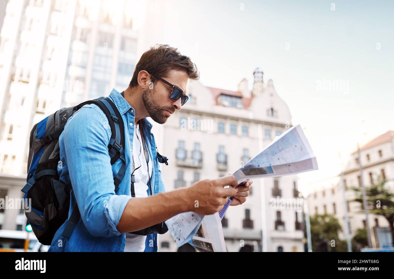 Wo bin ich? Ich habe einen hübschen jungen Mann auf einer Karte angeschaut, während er eine fremde Stadt bereist. Stockfoto