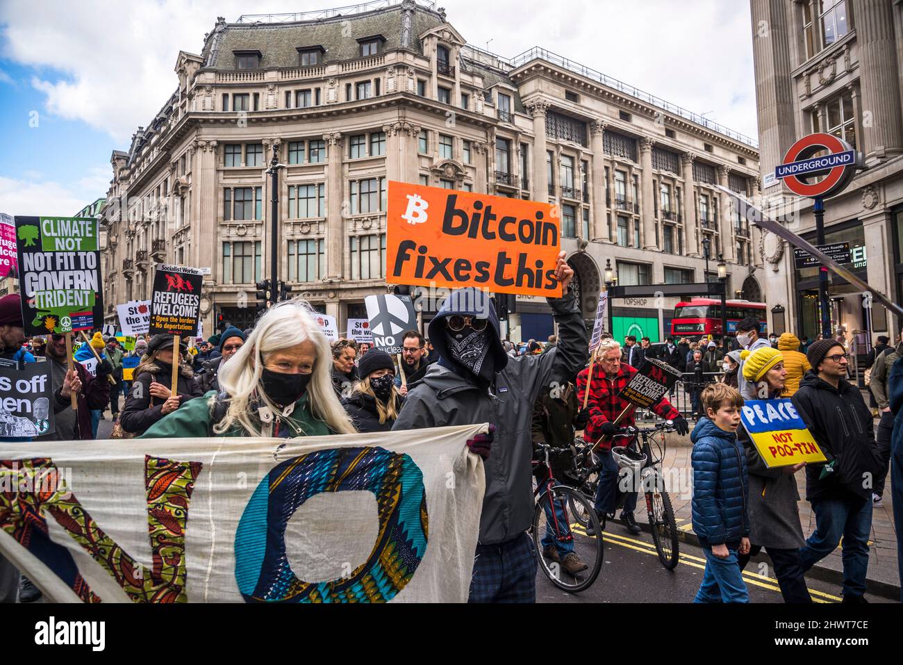 Maskierter Mann mit Plakat für Bitcoin, Stop the war Demonstration organisiert von Stop the war Coalition, London, Großbritannien, 6.. März 2022 Stockfoto