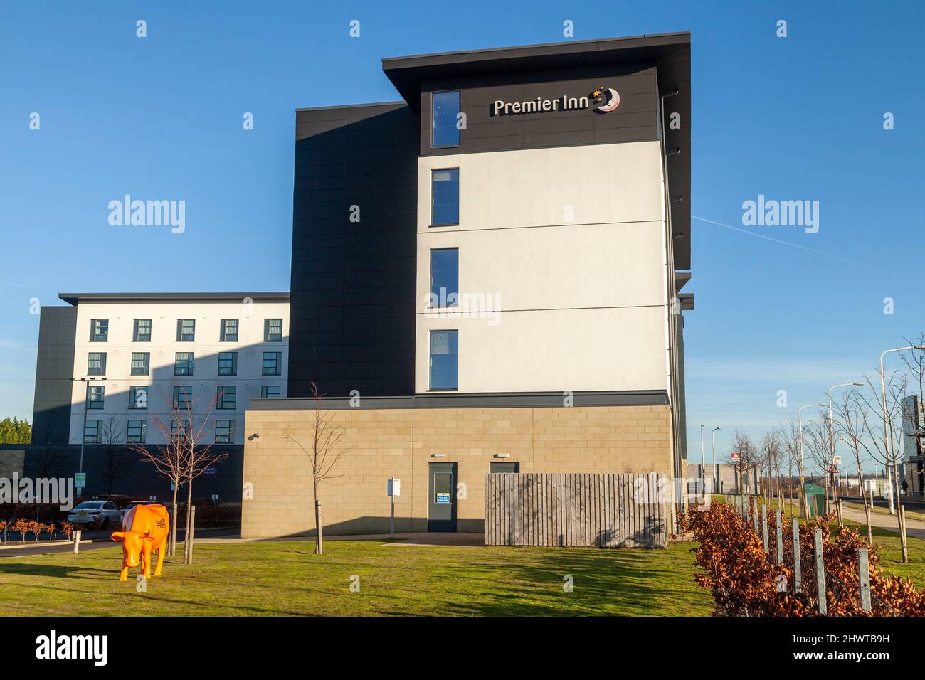 Eine orangefarbene Plastikkuh vor einem Premier Inn Hotel im Edinburgh Park, Edinburgh, Schottland. Stockfoto