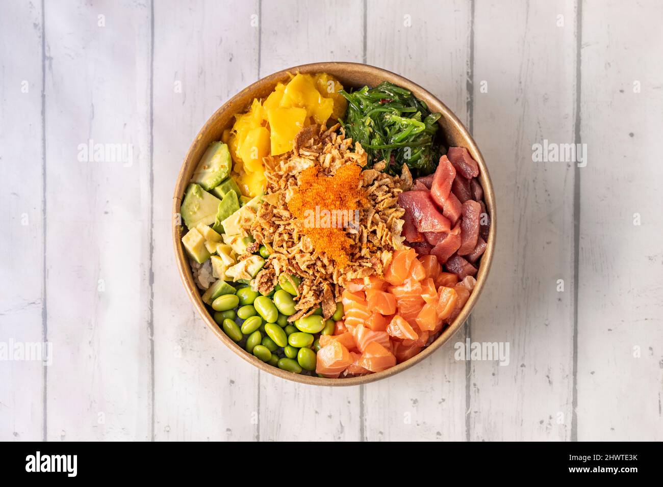 Gemischter norwegischer Lachs- und Blauflossen-Thunfisch-Poke-Schüssel mit knuspriger Zwiebel, Tobiko Masago Roe, reifer Mango, gewürfelter mexikanischer Avocado, weißer Reis, Wakame-Algen Stockfoto