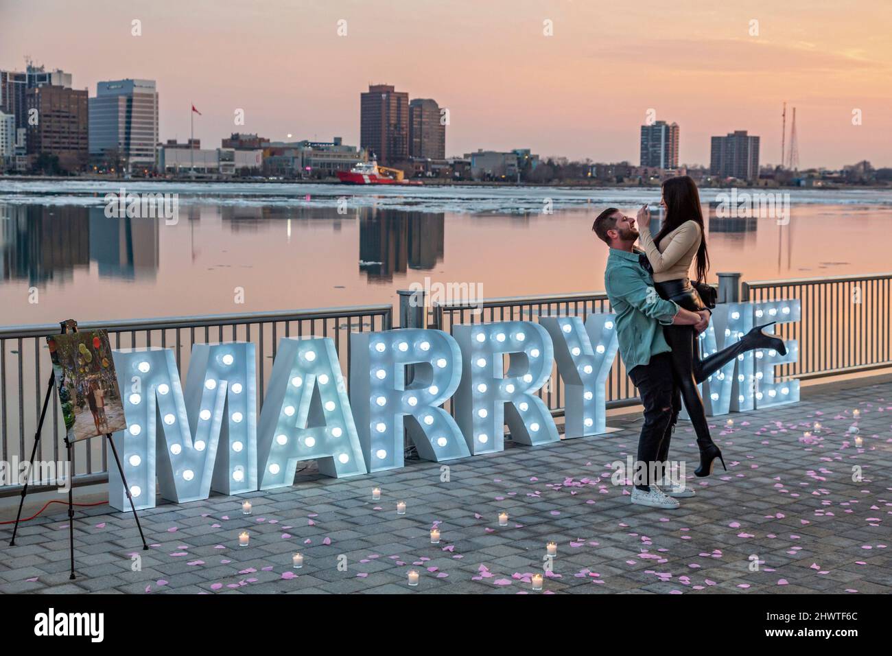 Detroit, Michigan - Ein glückliches Paar feiert entlang dem Detroit Riverwalk, nachdem der öffentliche Heiratsantrag des Mannes angenommen wurde. Stockfoto