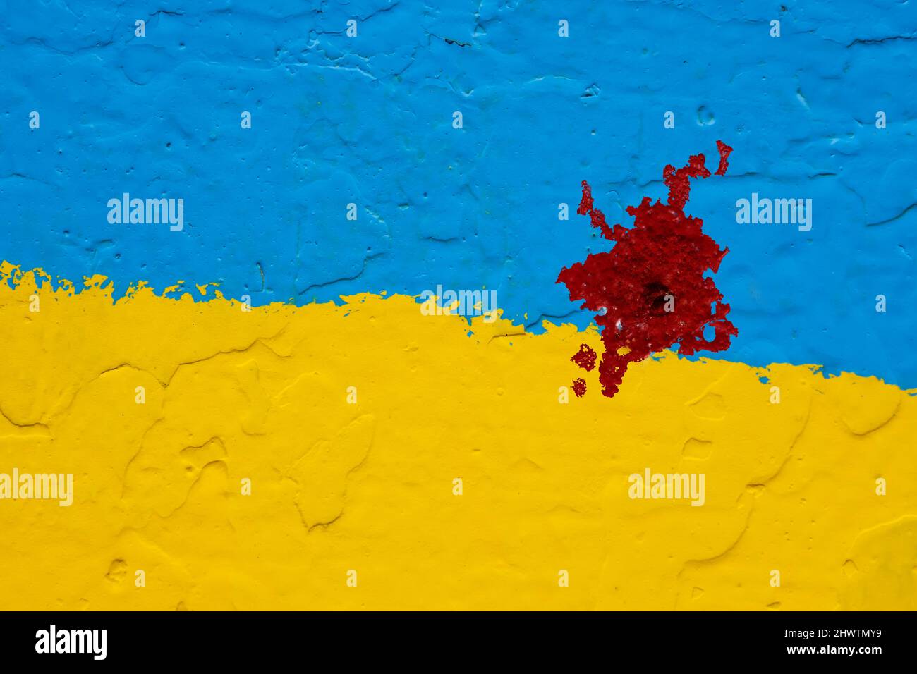 Die Betonwand ist gelb und blau gestrichen wie die ukrainische Flagge mit einem blutigen roten Fleck von einer Kugel Stockfoto