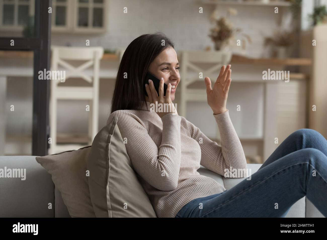 Junge Frau entspannen auf dem Sofa hält Smartphone nehmen, um Freund Stockfoto