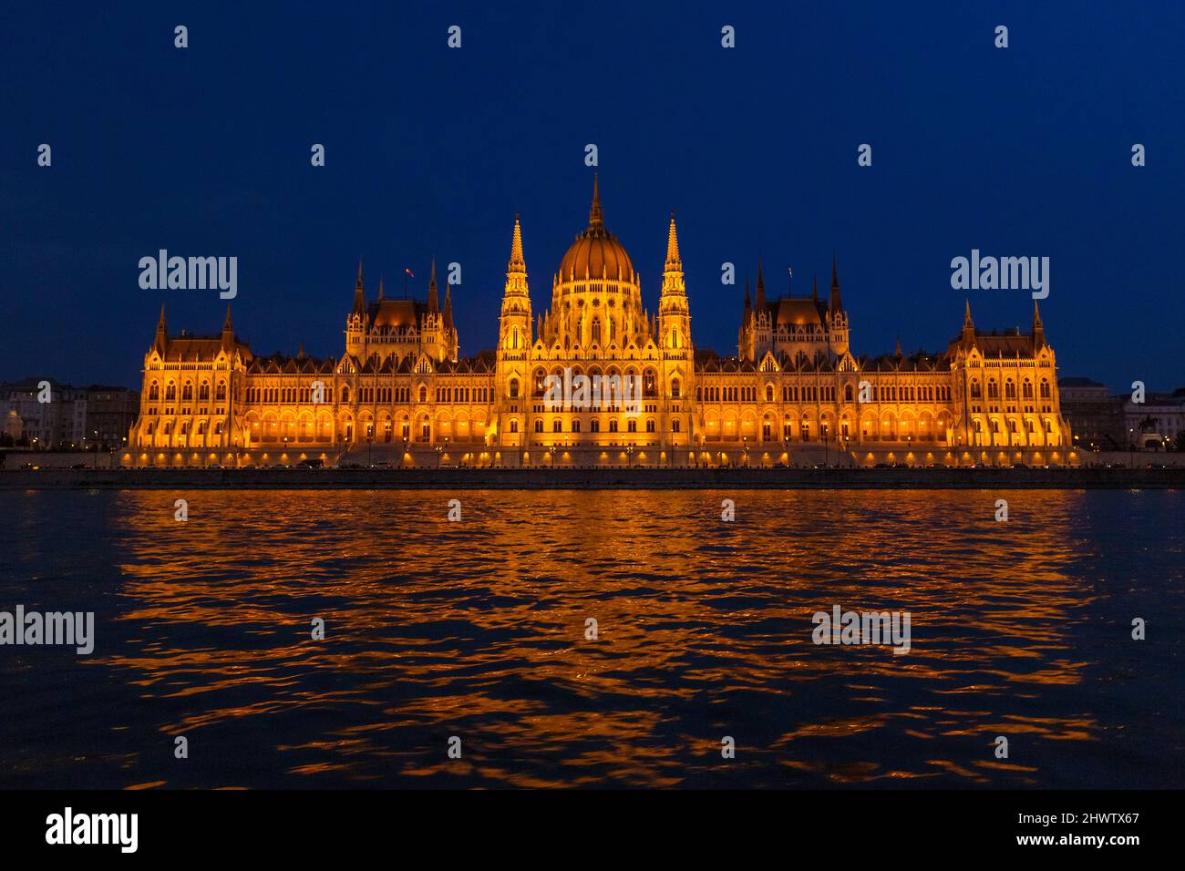 Das ungarische Parlamentsgebäude, ein bemerkenswertes Wahrzeichen Ungarns in Budapest. Blick auf die Hauptfassade beleuchtet über der Donau in der Nacht. Stockfoto