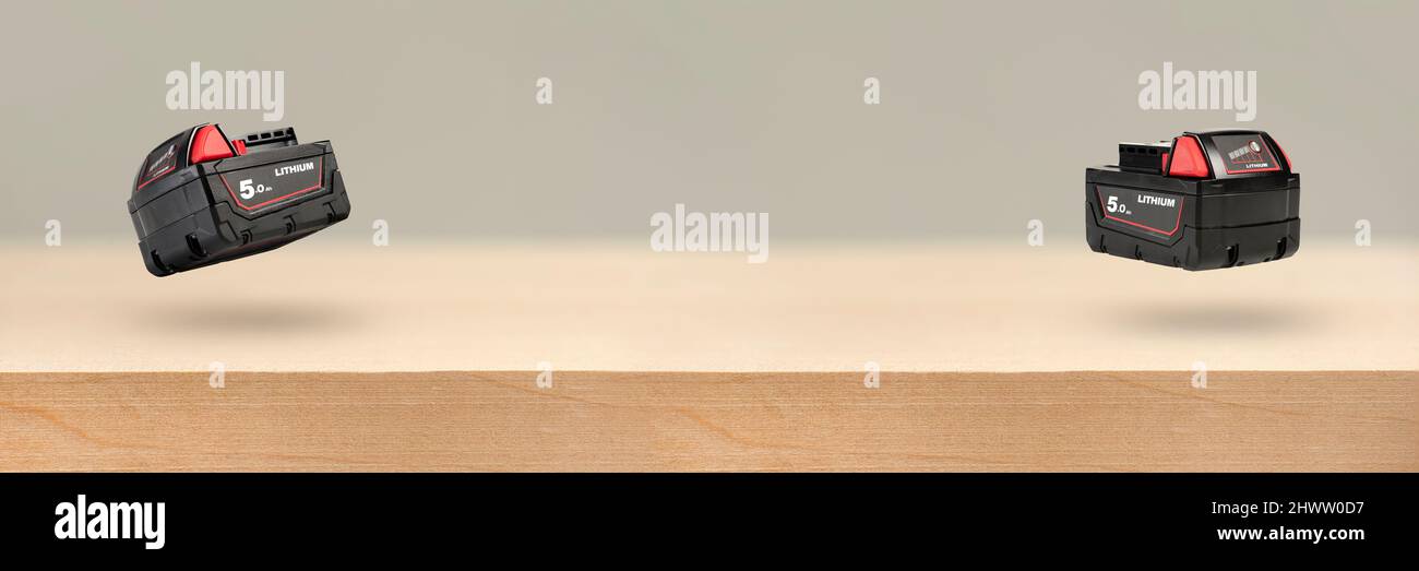 Akku für Akku-Bohrmaschine. Schrauberbatterie. Vier Batterien mit Ladeanzeige liegen auf einem Holzhintergrund Stockfoto