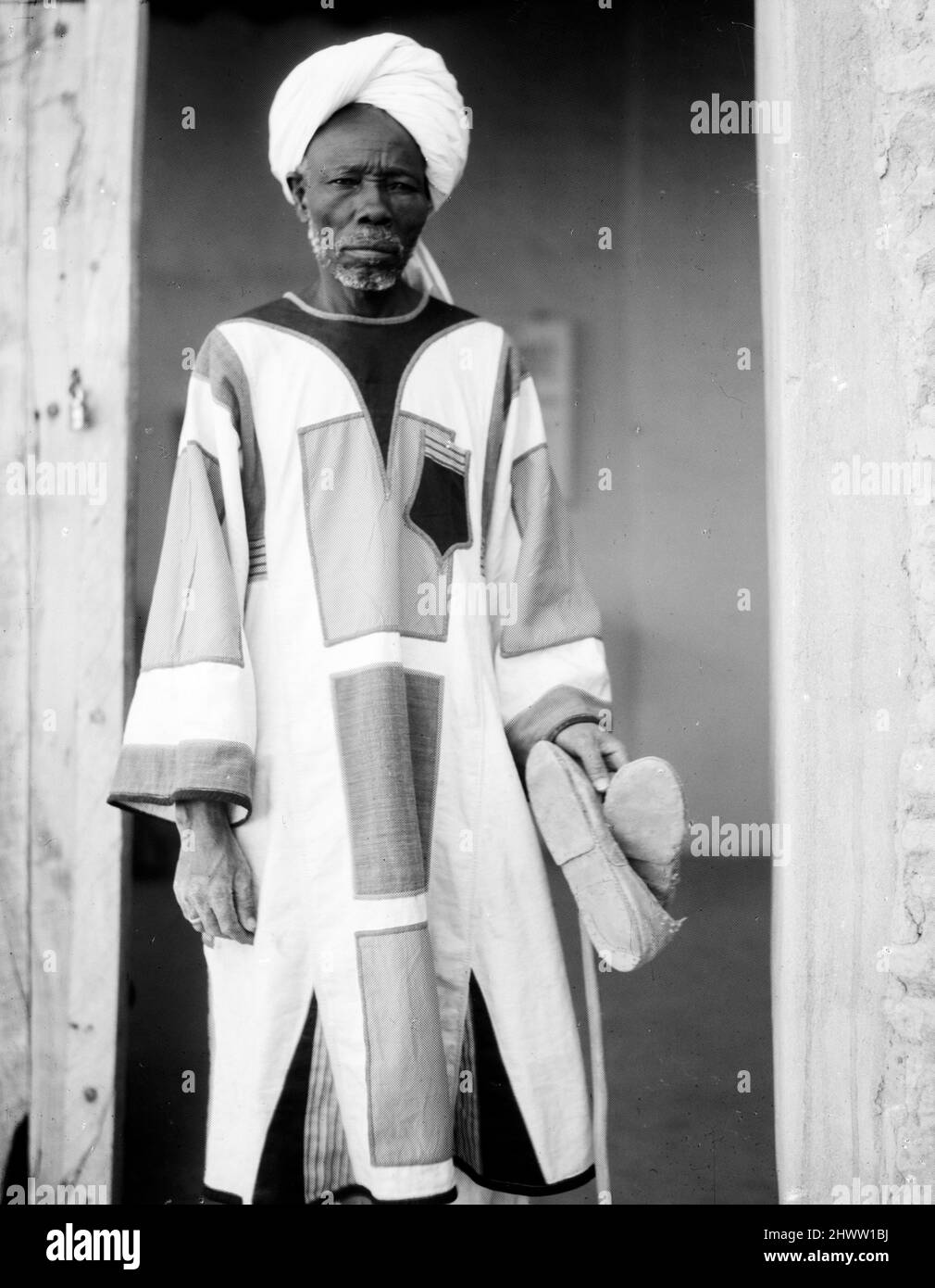 Ein sudanesischer Mann, der die typische Mahdistenjibba in Omdurman, 1936 Sudan trägt. Omdurman. Die Jibba oder Jibba ist ein langer Mantel, der von muslimischen Männern getragen wird. Stockfoto Ein sudanesischer Mann, der die typische Mahdistenjibba in Omdurman, 1936 Sudan trägt. Omdurman. Die Jibba oder Jibba ist ein langer Mantel, der von muslimischen Männern getragen wird. Stockfoto