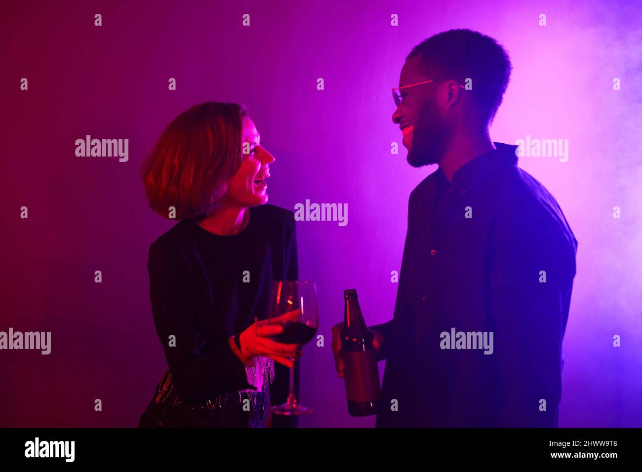 Minimal Taille up Porträt von jungen Paar lachen, während Party in Neonlicht genießen Stockfoto
