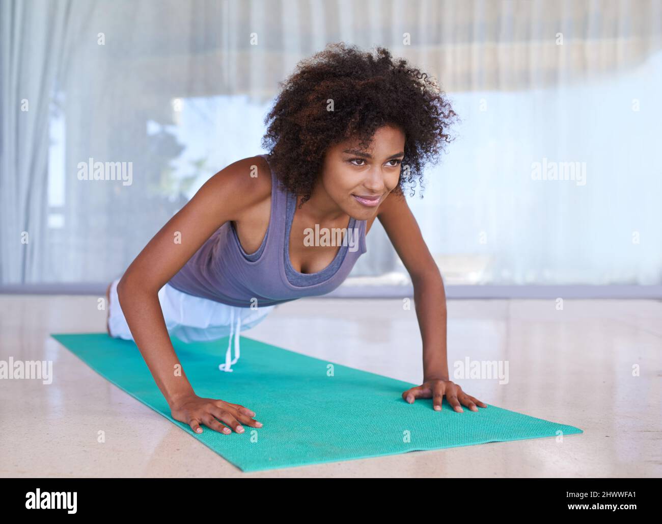 Arbeiten an ihrem Oberkörper. Aufnahme einer attraktiven jungen Frau, die Liegestütze auf einer Trainingsmatte macht. Stockfoto