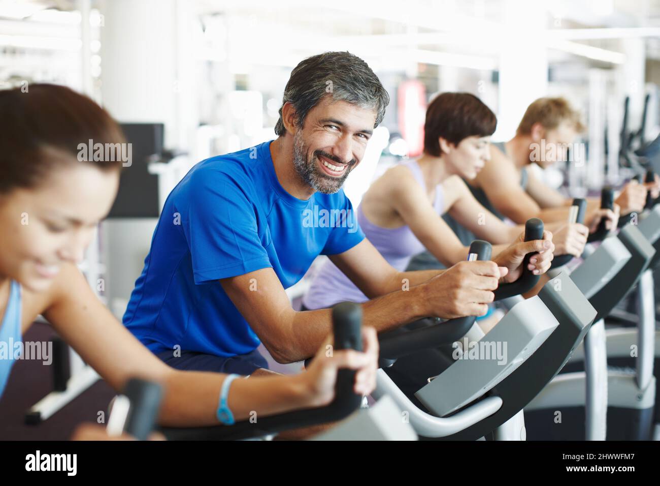 Ich bin fast fertig für den Tag. Eine kurze Aufnahme einer Reihe von Leuten, die im Fitnessstudio auf den Heimtrainern trainieren. Stockfoto