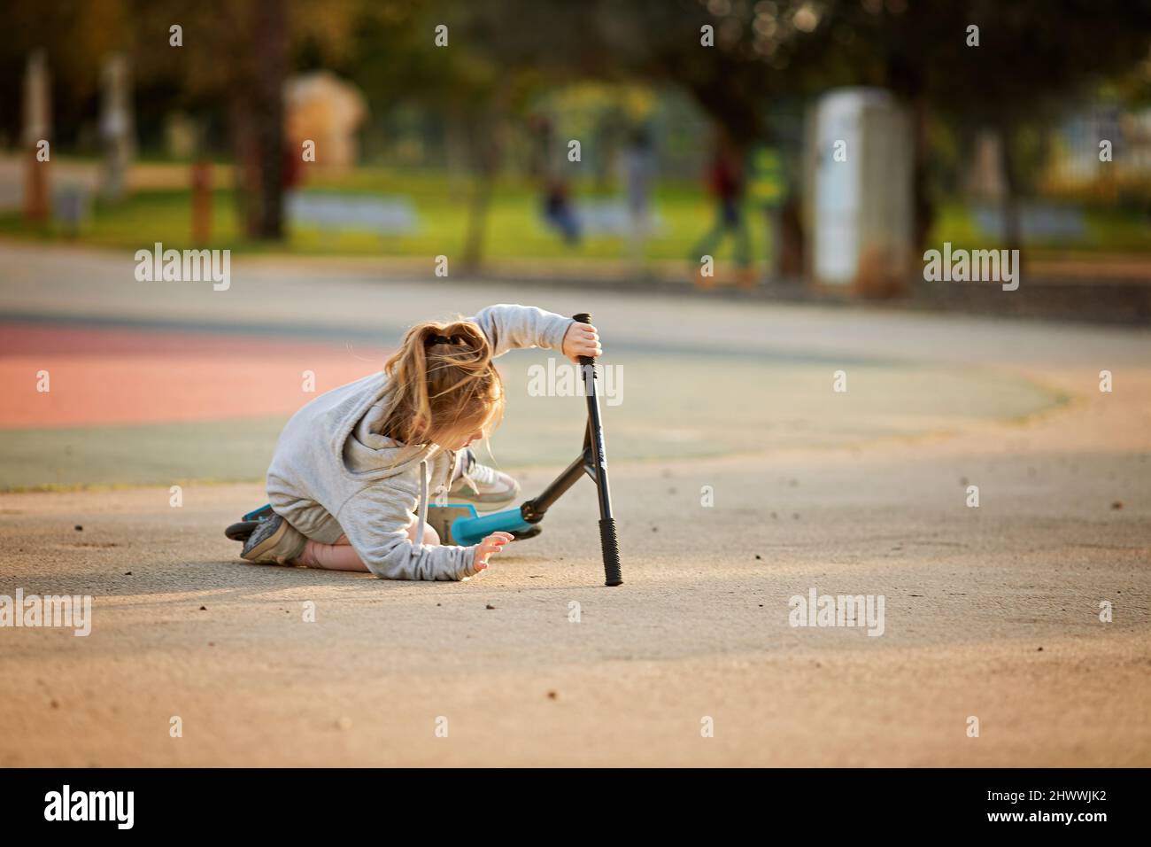 Kleines Mädchen fällt auf einen Roller im Park Stockfoto