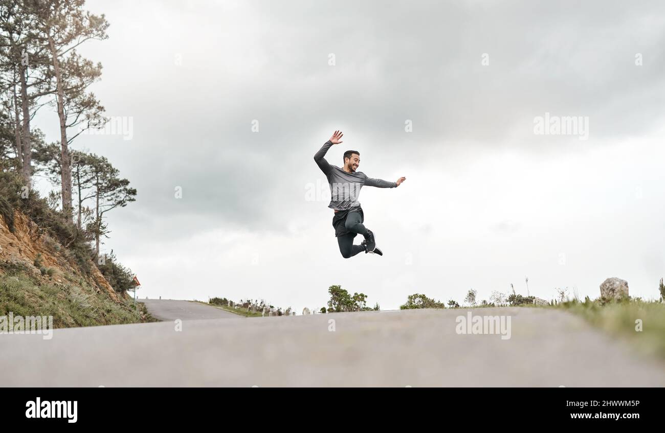 Ich habe einfach meine eigene Bestmarke geschlagen. In voller Länge ein hübscher junger Mann, der vor Freude nach seinem morgendlichen Lauf im Freien springt. Stockfoto
