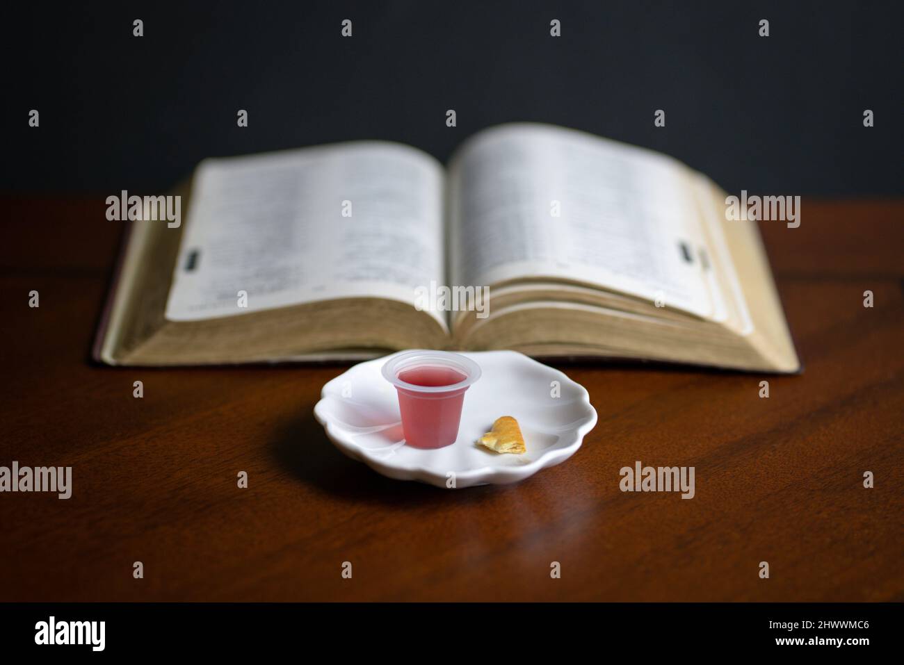 Christliches Abendmahl Sakramente, Wein und Brot mit offener Bibel im Hintergrund. Stockfoto