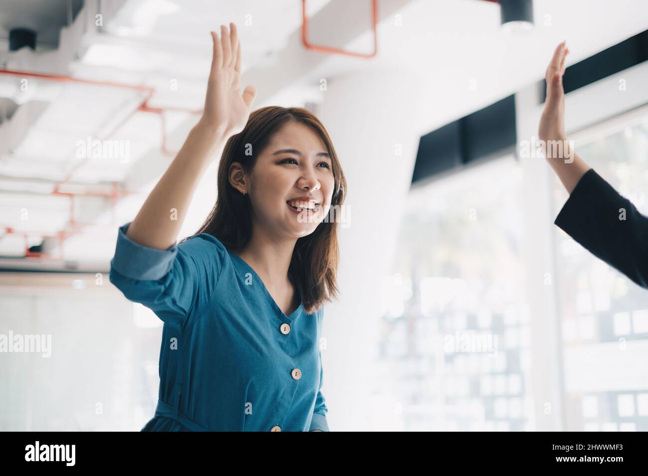 Die asiatische Geschäftsfrau und ihre Partner geben sich gegenseitig hohe Five, wenn sie ein erfolgreiches Team Building-Projekt feiern. Stockfoto