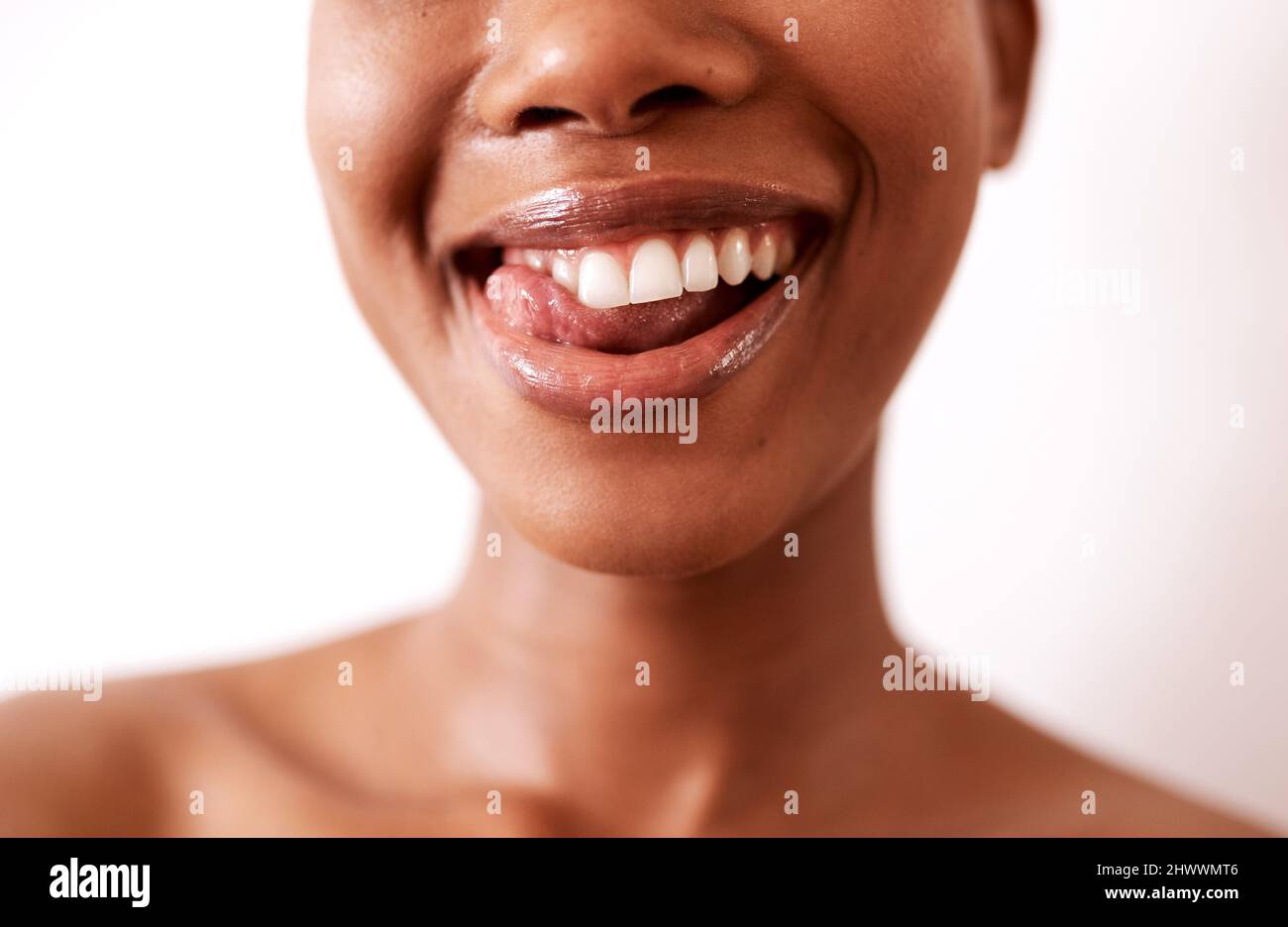Meine Zähne sahen nie so gut aus. Nahaufnahme einer schönen jungen Frau, die mit glänzenden Lippen vor weißem Hintergrund posiert. Stockfoto