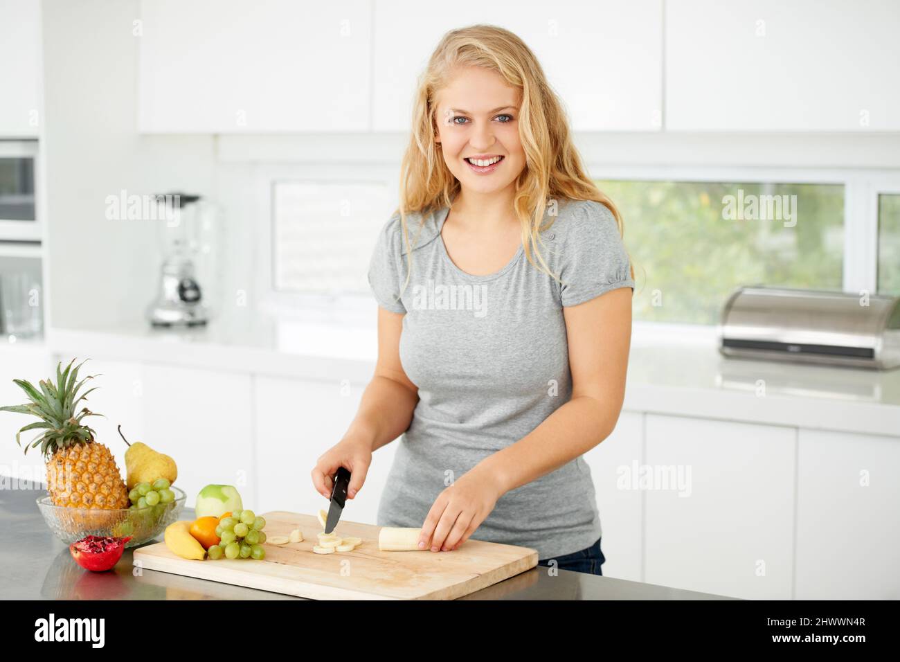 Nichts ist besser als frisches Obst. Attraktive kurvenreiche junge Frau, die in ihrer Küche Obst hackt. Stockfoto
