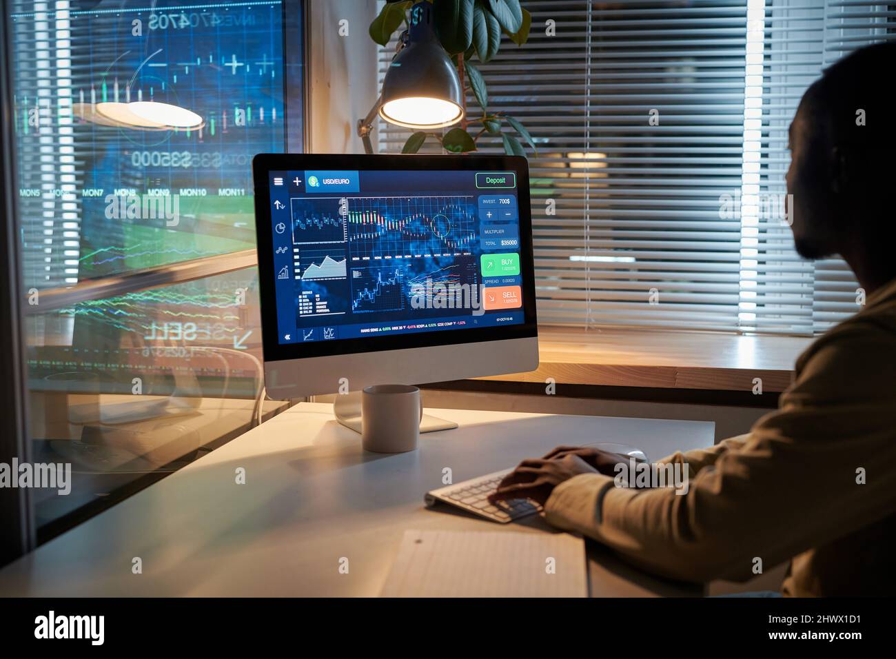 Rückansicht des afrikanischen Geschäftsmannes, der während der Frist Computermonitor ansah und mit Software am Tisch im Büro arbeitete Stockfoto