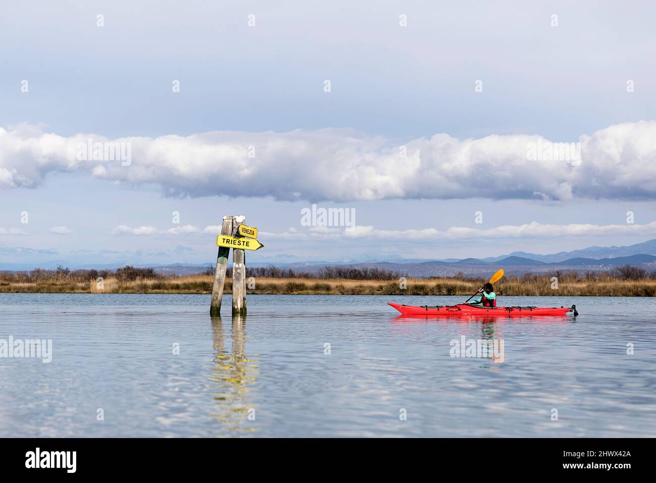 Frau mit dem Kajak auf dem Meer, erkunden die Mündung des Isonzo (Fluss Soča) und halten an der Beschilderung "Regional Nature Reserve of the Foce dell'Isonzo, Italien" Stockfoto