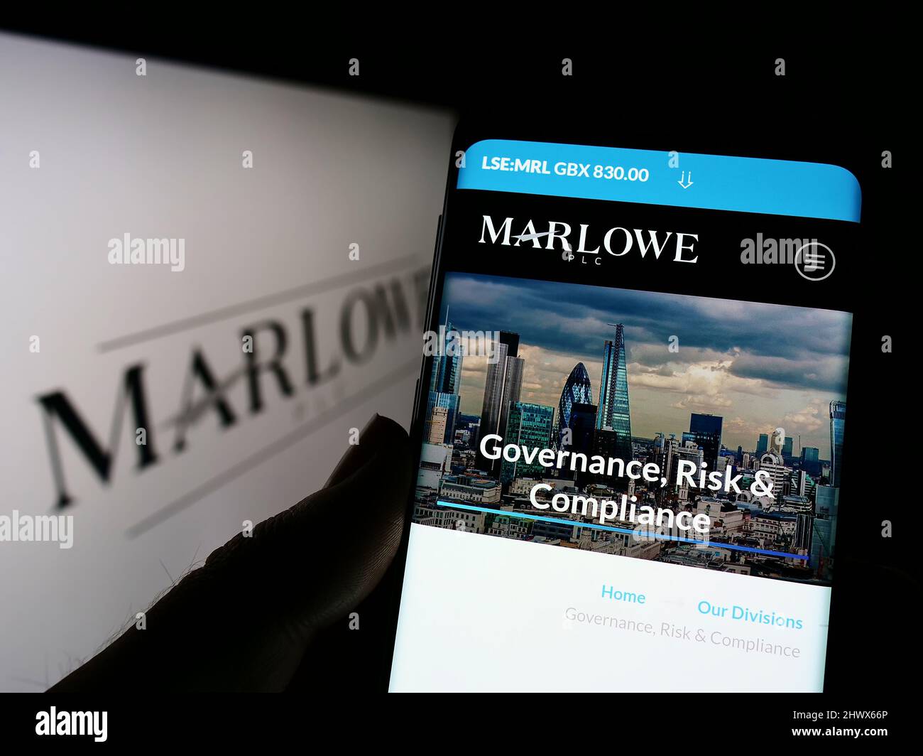 Person, die Mobiltelefon mit der Webseite des britischen Compliance-Unternehmens Marlowe plc auf dem Bildschirm vor dem Logo hält. Konzentrieren Sie sich auf die Mitte des Telefondisplays. Stockfoto