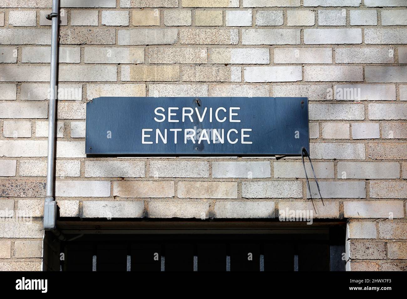 Auf einem Schild über einem Tor steht: „Serviceeingang“ in einem Wohngebäude in New York City. Separater Eingang für Servicemitarbeiter, Handwerker, Lieferung Stockfoto