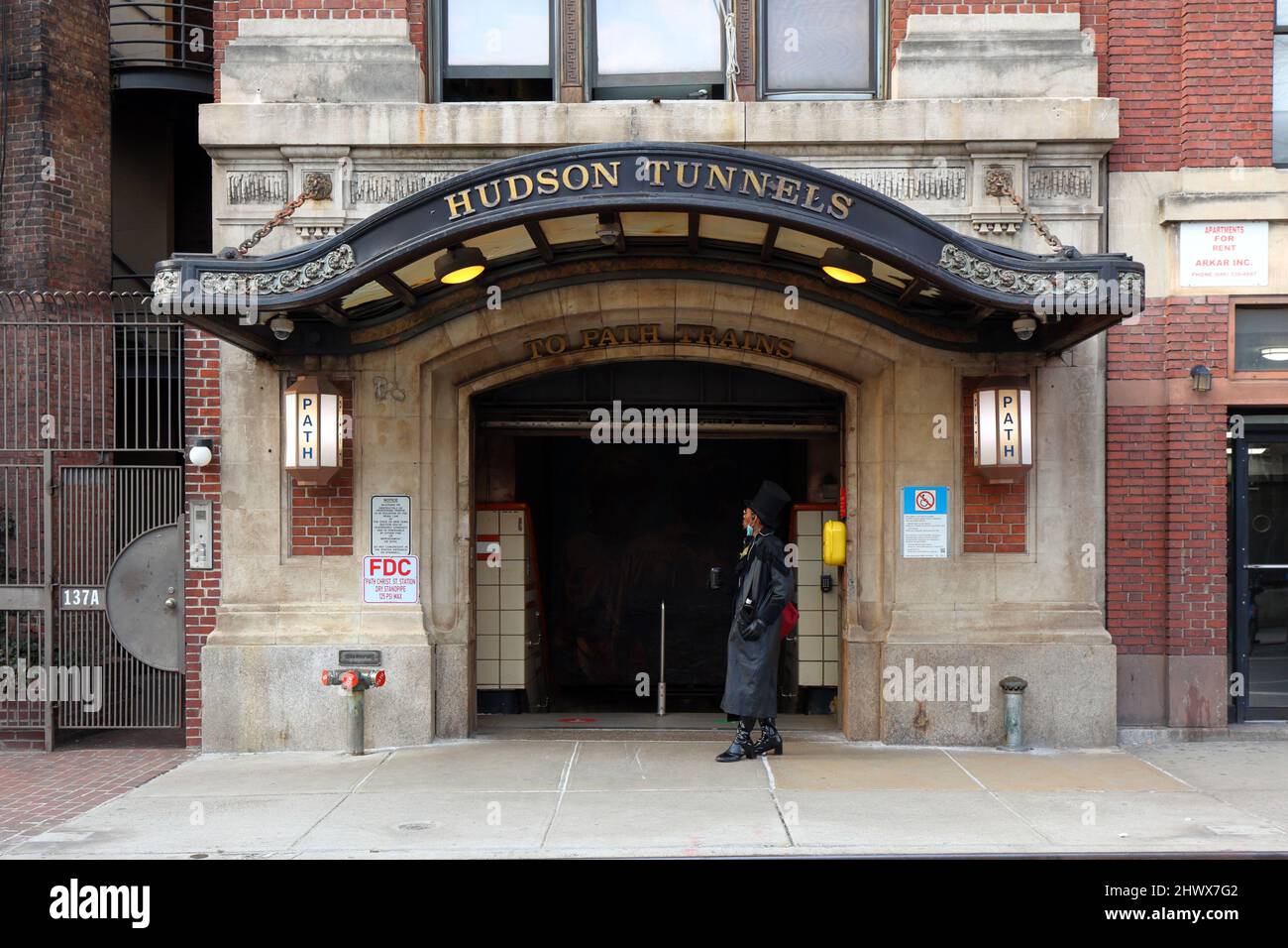 Eine Person mit einem Hut geht an der U-Bahn-Station Christopher St PATH im West Village Viertel von Manhattan, New York vorbei. Stockfoto Eine Person mit einem Hut geht an der U-Bahn-Station Christopher St PATH im West Village Viertel von Manhattan, New York vorbei. Stockfoto