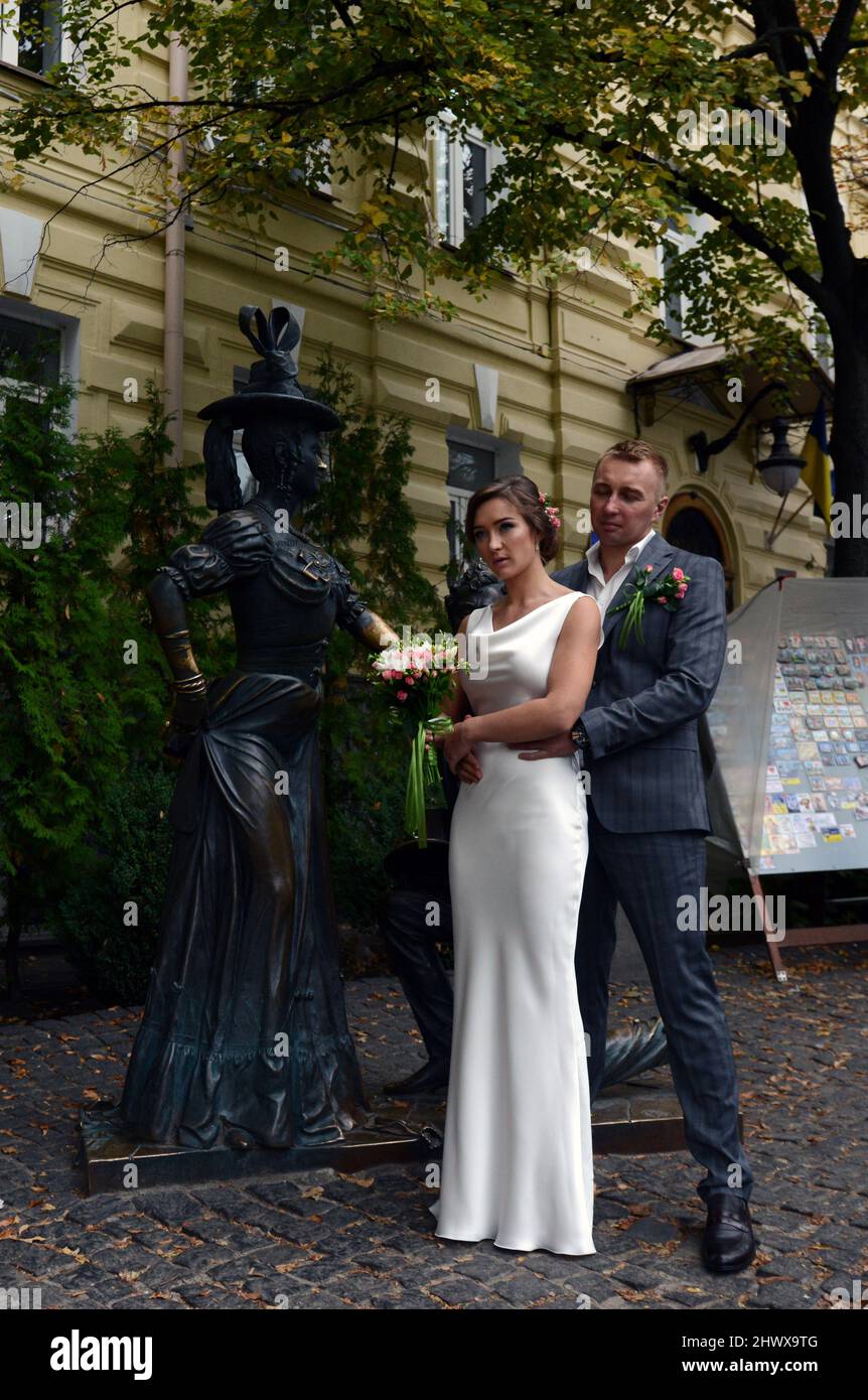 Ukrainische Jungvermählte posieren für ein Bild der Pronya Prokopivna und Svirid Holokhvastov Skulptur auf Andriivskyi Abstieg in Kiew, Ukraine. Stockfoto